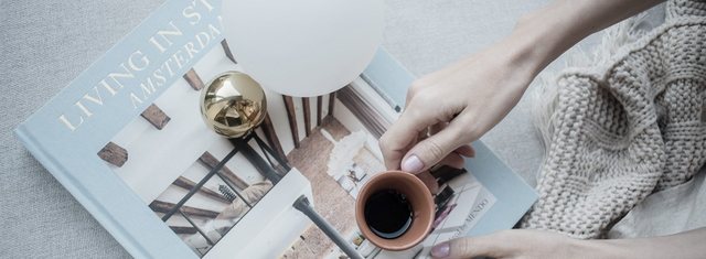 Abajur Graça sobre livros de arquitetura, com uma xícara ao lado.