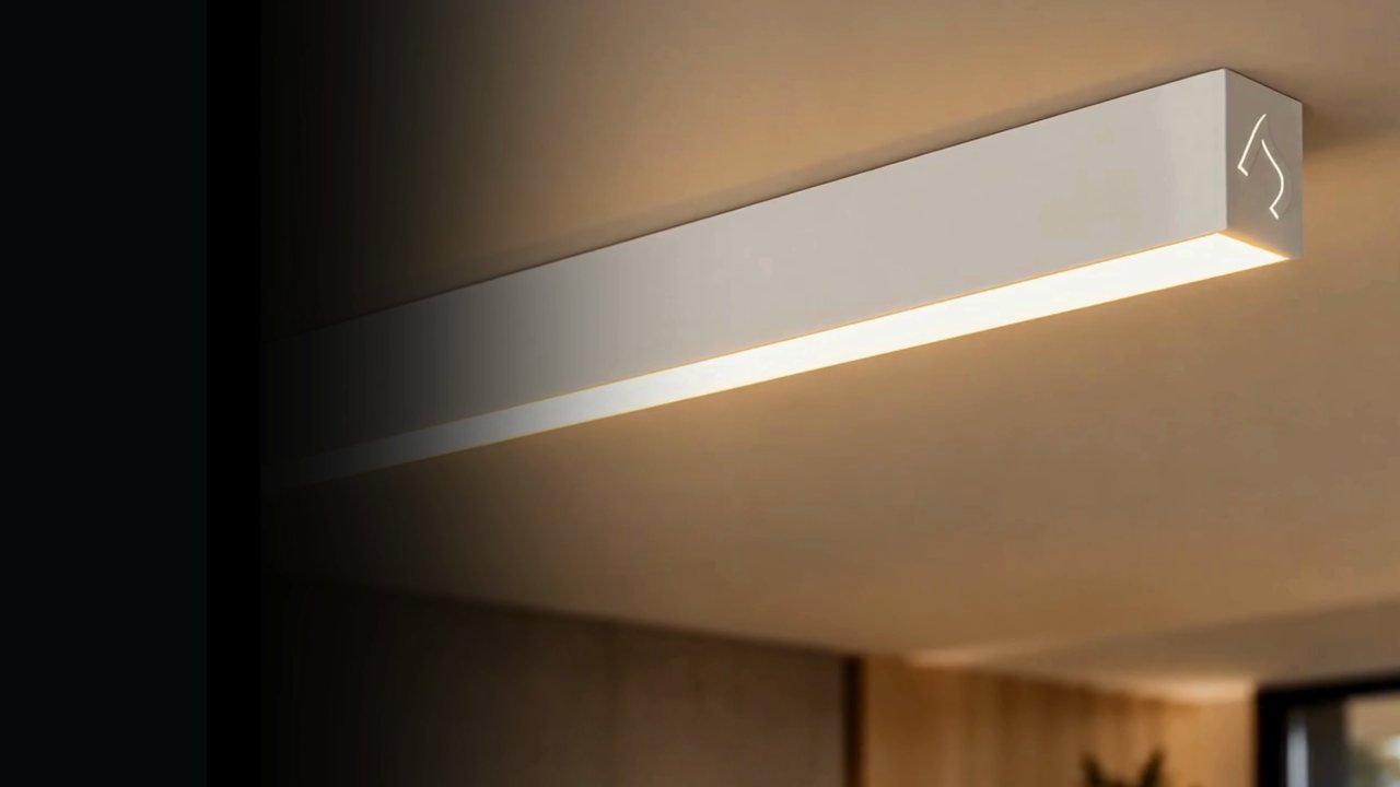 Perfil de LED Direct de sobrepor aceso no teto de um ambiente com painel de madeira.