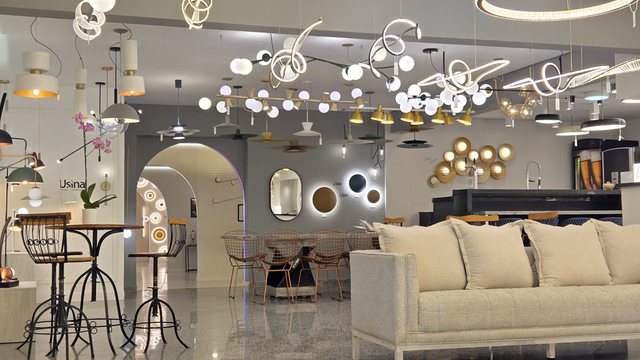 Área de estar do showroom da Usina Design, com o arco e a parede de espelhos