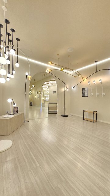 Corredor de piso claro do showroom da Usina, com pendentes em fileira